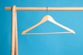 Empty clothes hanger on wooden rack against light blue background Royalty Free Stock Photo