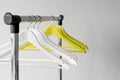 Empty clothes hangers on metal rail against grey background. Rectangular metal clothing rail with empty color wooden