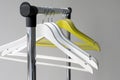 Empty clothes hangers on metal rail against grey background. Rectangular metal clothing rail with empty color wooden