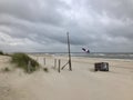 empty coastline in a Dutch North sea in a stormy, windy, gray day. flag waving on flagpole.