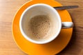 Empty coffee cup with rest of cappuccino on an orange saucer Royalty Free Stock Photo