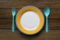 Empty color plate, fork and spoon on wooden table background Royalty Free Stock Photo