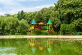 Empty colorful children playground castle with green lush vegetation background and water lake reflection in the foreground situat Royalty Free Stock Photo