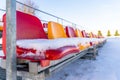 Empty Colorful Football Soccer Stadium Seats in the Winter Covered in Snow - Sunny Winter Day with Clear Blue Sky in the Royalty Free Stock Photo