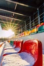 Empty Colorful Football (Soccer) Stadium Seats in the Winter Covered in Snow - Sunny Winter Day with Sun Flare Royalty Free Stock Photo