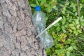 An empty compressed plastic bottle is nailed to a tree