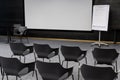 Empty conference room with rows of grey chairs, media screen and whiteboard Royalty Free Stock Photo