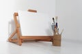 Empty copy space canvas on wood easel and paintbrush in artistic workshop interior