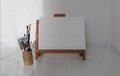 Empty copy space canwas on wood easel and paintbrush in artistic workshop interior