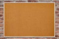 An empty cork board is hanging on a brick wall. Copy space Royalty Free Stock Photo