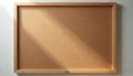 Empty cork board with wooden frame hangs on white wall. Light casts diagonal shadow across surface. Ideal for notes, memos, or Royalty Free Stock Photo