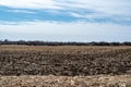Empty corn field after fall harvest with residue over soil. Urban sprawl visible in the distance with residential Royalty Free Stock Photo