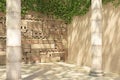 Empty corner of an ivy-covered decorative wall and old columns. Wall of stone blocks and bricks with pattern in ancient style.