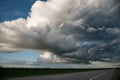 Empty country asphalt road with dramatic voluminous evening clouds before a thunderstorm. Beautiful weather clouds