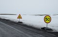 Empty countryside road with snow and warning signs