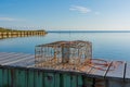 An empty crab trap sits on a boardwalk on an a bayfront property.