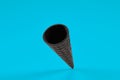 Empty, crispy black wafer cone for ice cream on blue background. Concept of food, treats. Mockup, template for your