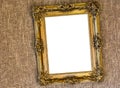 Empty crooked hanging antique expensive looking golden painting frame hanging on a sackcloth wall
