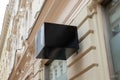 Empty cube-shaped black sign on street building facade for logo mockup