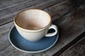 Empty cup of coffee in earthern ware cup with saucer on rustic wooden table Royalty Free Stock Photo