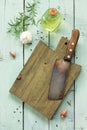 Empty cutting board and ÃÂ°ncient meat knife on a wooden culinary background, various spices and rosemary.