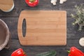 Empty cutting board on wooden desk surrounded with vegetables, mushrooms, spice box, plant, milk bucket