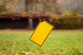 Empty, damaged yellow warning sign hanging on a dirty chain in the park