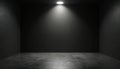 Empty dark room with single bright spotlight illuminates grey concrete floor, textured back wall. Minimal, stark interior space Royalty Free Stock Photo
