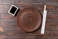 Empty dark vintage round plate with chopsticks for sushi on wooden background. Top view with copy space Royalty Free Stock Photo