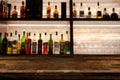 Empty dark wooden bar counter with blur background bottles. Royalty Free Stock Photo