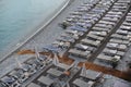 Empty deck chairs with mattresses and umbrellas on a pebble beach on Mediterranean sea coast in summer Royalty Free Stock Photo