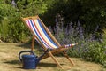 An empty deckchair and watering can in country garden, Royalty Free Stock Photo