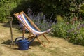 An empty deckchair, watering can and a garden fork Royalty Free Stock Photo