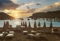 Empty deckchairs on the Cala Vadella beach in Ibiza Island during beautiful right sunset, moored luxury yachts in the