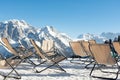 Empty deckchairs stand in the snow against the backdrop of snow-capped mountains. The concept of vacation, landscape. Royalty Free Stock Photo