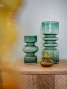 Empty decorative vases from transparent glass on wooden cupboard with blured foreground. Interior decoration