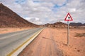 Empty desert road at Wadi Rum, red triangle warning camels sign near Royalty Free Stock Photo