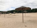 An empty deserted beach in bad weather, cold autumn in the off-season with thatched sun umbrellas against the blue sky Royalty Free Stock Photo