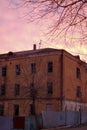 Empty destroyed building with broken windows. Pink sky Sunset. Photo in red colors. The oppressive atmosphere of destruction. Royalty Free Stock Photo