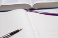 Empty diary or notepad and fountain pen with golden nib closeup, thick opened book in background