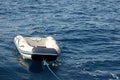 An empty dinghy floats on the waves of the blue sea, tied with a rope to a yacht. Sunny goddess on the sea. Safety on the water Royalty Free Stock Photo