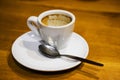 An empty dirty cup with the remains of coffee on the brown table.