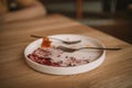 Empty dirty dish after cheesecake with berry sauce and dessert fork. White rustic trendy modern fashionable dirty plate Royalty Free Stock Photo