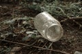 Empty dirty glass jar on the ground among grass and branches Royalty Free Stock Photo