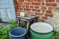 Empty dishes for water and soap lying on a stool against a brick wall in spring-summer day outdoors. Means for washing in housing