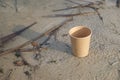 The empty disposable paper cup on the sandy beach.