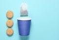 Empty disposable paper cup for tea, tea bag, cookies on blue pastel background, top view, minimalism. Royalty Free Stock Photo