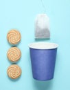 Empty disposable paper cup for tea, tea bag, cookies on blue pastel background, top view, minimalism. Royalty Free Stock Photo