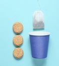 Empty disposable paper cup for tea, tea bag, cookies on blue pastel background, top view, minimalism. Royalty Free Stock Photo