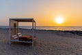 Empty double sun bed with pillows on the sandy beach in Dubai, with orange sunset in the background and calm sea Royalty Free Stock Photo